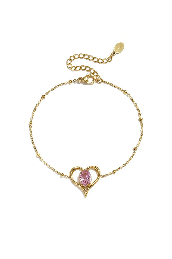 A gold-plated stainless steel chain station bracelet featuring a central open heart pendant with a prong-set oval pink cubic zirconia stone. amelie-pink-solitaire-heart-bracelet.webp