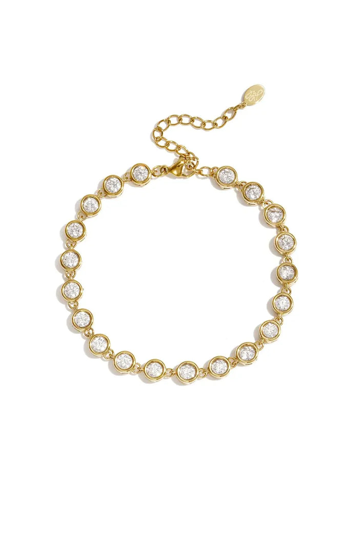 A gold-plated stainless steel bracelet featuring a continuous strand of round cubic zirconia crystal stations with a lobster clasp and extender chain against a white background. clara-solitaire-crystal-tennis-bracelet.webp