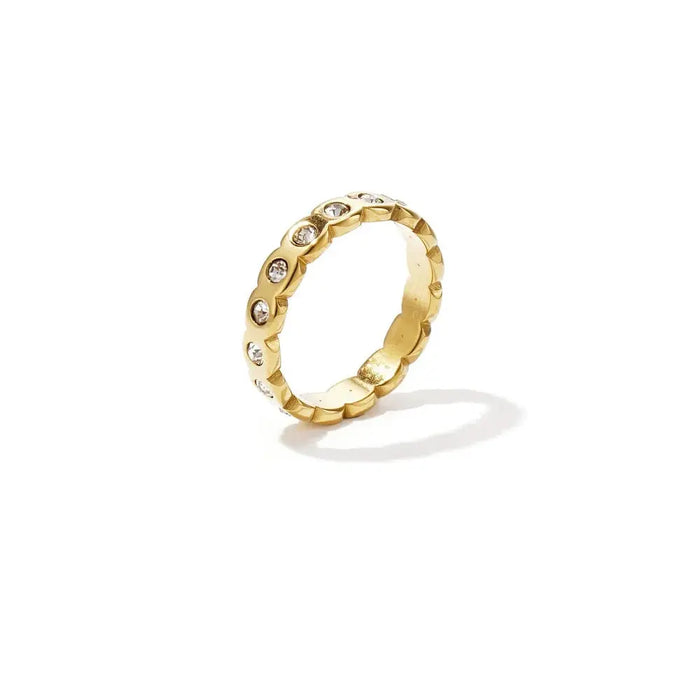 A tarnish-free gold-plated stainless steel eternity band ring featuring a continuous scalloped wave silhouette set with small circular clear bezel cubic zirconia crystals. lumi-waterproof-cz-eternity-band.webp