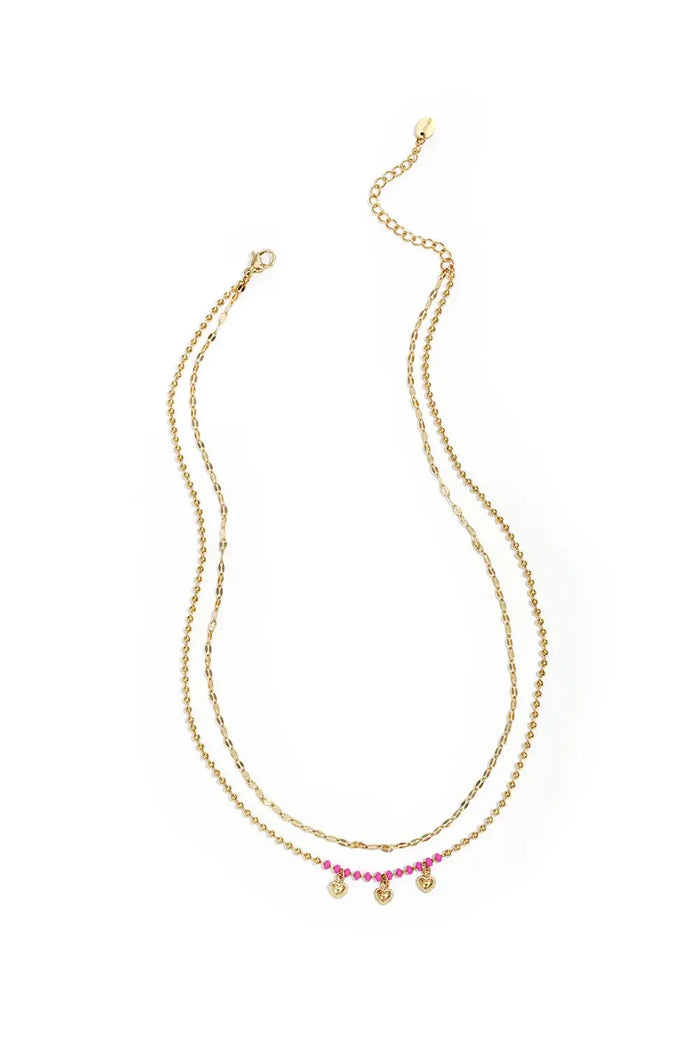 A gold-plated stainless steel multi-layer necklace featuring a top tier textured gold chain and a bottom tier gold satellite chain decorated with hot pink seed beads and three small hanging heart charms. mimi-multi-layer-heart-fringe-necklace.webp