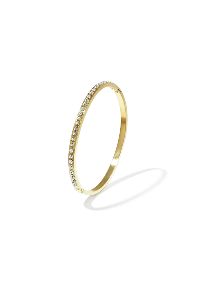 A gold-plated stainless steel hinged bangle featuring a continuous row of flush-set clear cubic zirconia crystals against a white background. serena-pave-crystal-gold-bangle.webp