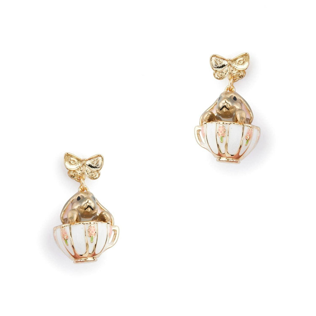 A pair of Bill Skinner gold drop earrings featuring a structured gold bow stud suspending a miniature white enamel teacup with a gold bunny inside.