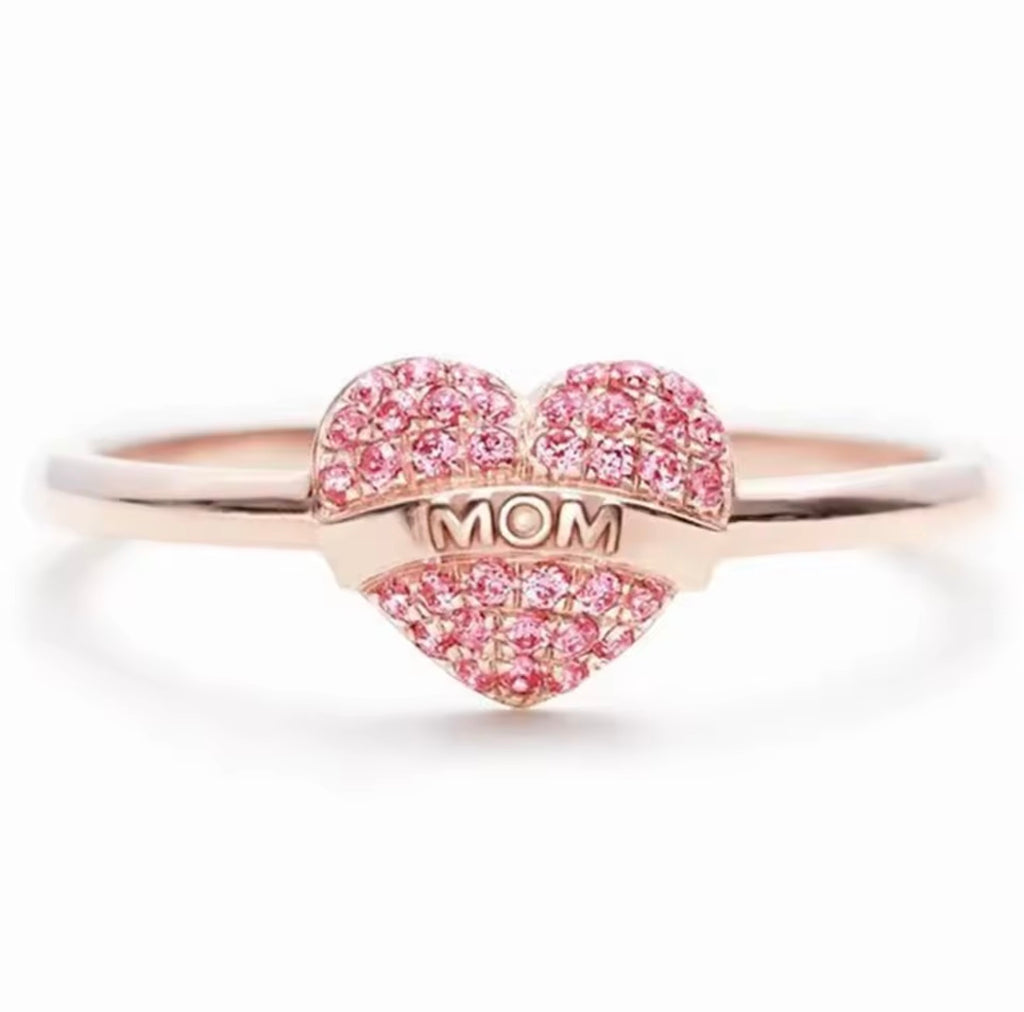 A 925 sterling silver ring featuring a central puffy heart densely set with pink pavé crystals and a polished banner across the center embossed with the word MOM.