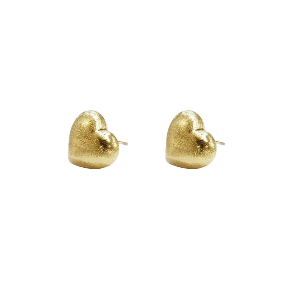 A pair of gold-plated stud earrings featuring a three-dimensional puffy heart shape with a unique matte hand-brushed satin finish. amour-brushed-heart-studs.webp
