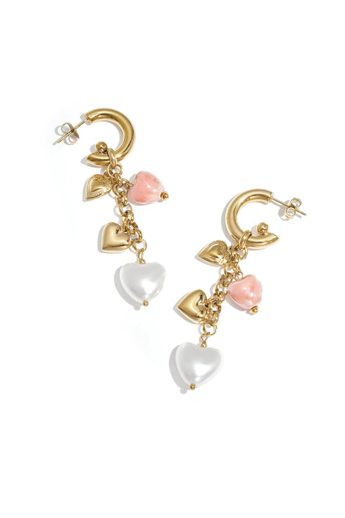 A pair of gold-plated half-hoop drop earrings featuring a cascading chain of charms including a flat gold heart, a 3D gold puffy heart, a marbled pink heart bead, and a large white pearl heart drop. amour-cascade-heart-earrings.webp