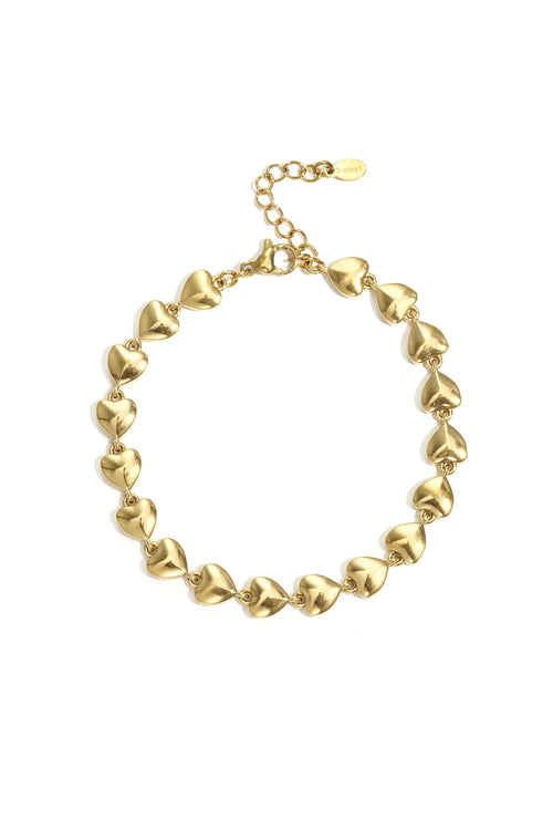 A gold-plated stainless steel bracelet featuring a continuous line of linked puffed heart stations with a lobster clasp and extender chain against a white background. aria-puffed-heart-chain-bracelet.webp