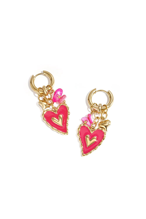 Pair of gold huggie hoop earrings featuring a cluster of charms including a scalloped hot pink enamel heart, a mini gold heart, and bright pink beads on a white background.