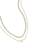 A gold-plated stainless steel multi-layer necklace featuring a top tier clear cubic zirconia tennis chain and a bottom tier gold snake chain with a flat heart charm. cherie-multi-layer-tennis-heart-necklace.webp