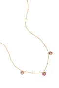 A delicate gold-plated satellite chain necklace featuring three open-heart charm stations encrusted with soft pink and rich magenta pavé crystals. colette-multi-heart-necklace.jpg