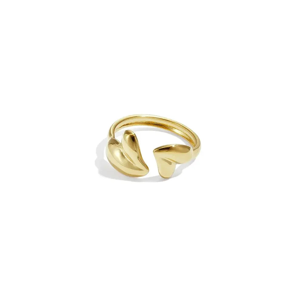 A gold-plated stainless steel bypass ring featuring a wrap band adorned with two asymmetrical three-dimensional puffy gold hearts against a plain white background. cora-puffy-heart-bypass-ring.webp