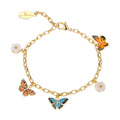 A gold-plated charm bracelet by Bill Skinner featuring hand-painted enamel charms of a blue butterfly, an orange butterfly, an earth-tone butterfly, and two white flowers on a link chain. bill-skinner-butterfly-charm-bracelet.webp