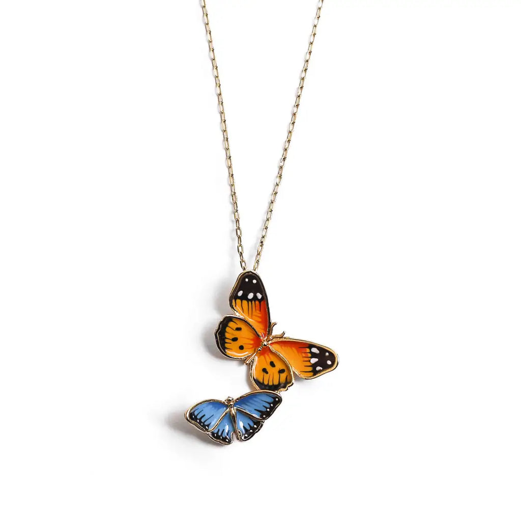 A gold-plated pendant necklace by Bill Skinner featuring a stacked design of two hand-painted enamel butterflies—one large orange monarch and one small blue butterfly. bill-skinner-dual-butterfly-necklace.webp