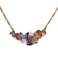 A spectacular gold-plated statement bib necklace by Bill Skinner featuring hand-painted enamel blue and orange butterflies, a purple rose, white flowers, berries, and colorful crystal rhinestones. bill-skinner-butterfly-bib-necklace.webp