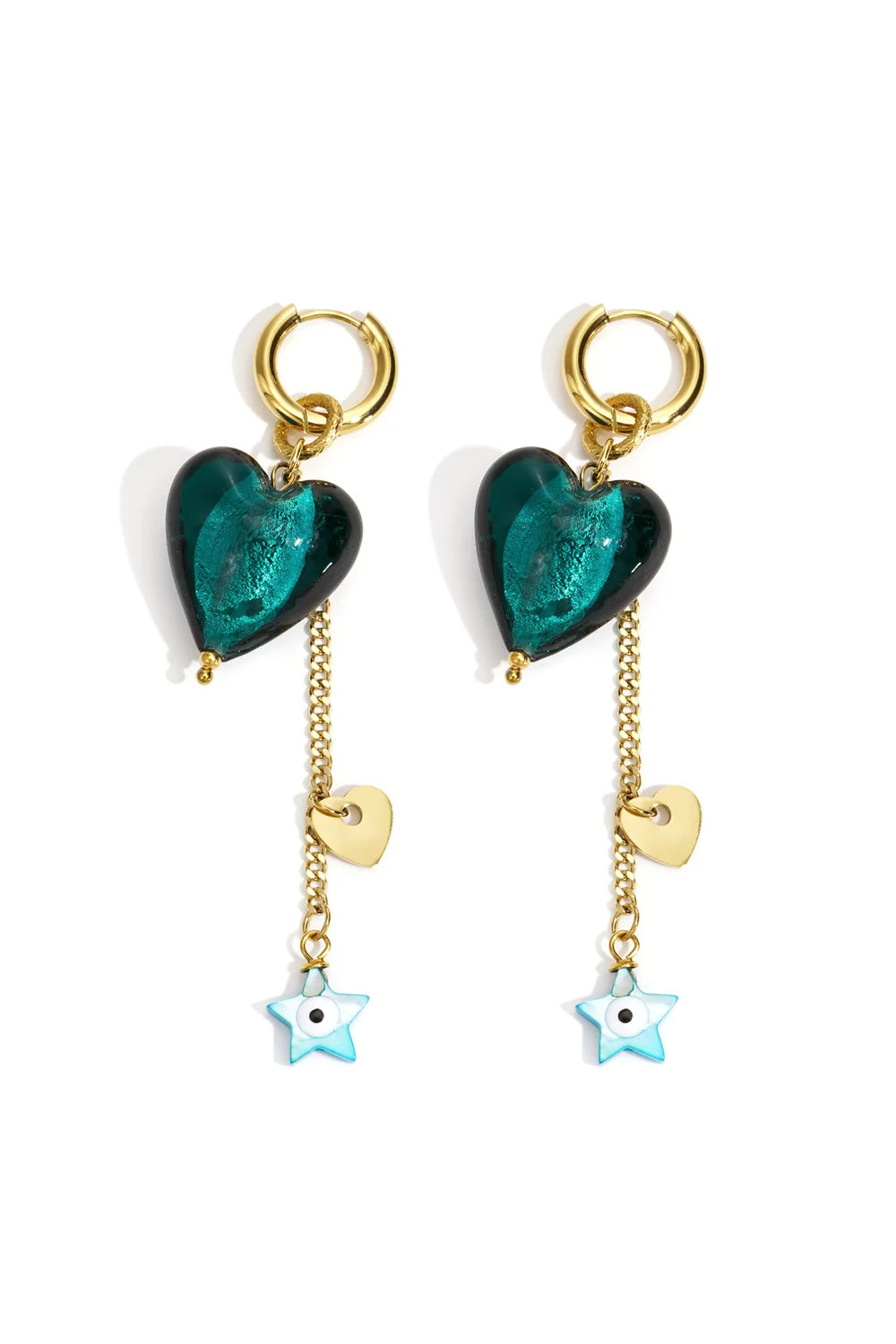 A pair of gold-plated stainless steel huggie hoop earrings featuring a dangling emerald green glass heart alongside a gold link chain decorated with a small gold heart and a turquoise star evil eye charm. esme-murano-heart-celestial-drop-huggie-earrings.webp
