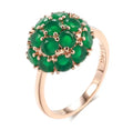 A structural 585 plated rose gold cocktail ring featuring a prominent raised dome cluster of vibrant translucent forest green round crystals on a white background.