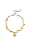 A gold-plated stainless steel double-layer charm bracelet featuring a central gold flower pendant, crystal flower charms, a heart station, a white pearl, and small yellow and pink beads against a white background. fleur-layered-charm-bracelet.webp