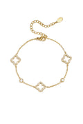A delicate gold-plated stainless steel chain station bracelet featuring three open quatrefoil clovers lined with clear pavé crystals alternating with two round bezel-set crystal solitaires. giselle-open-clover-bracelet.webp