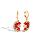 A pair of gold hoop earrings with crescent-shaped red gemstone clusters, accented by small green stones and a central clear crystal, shown on a white background.
