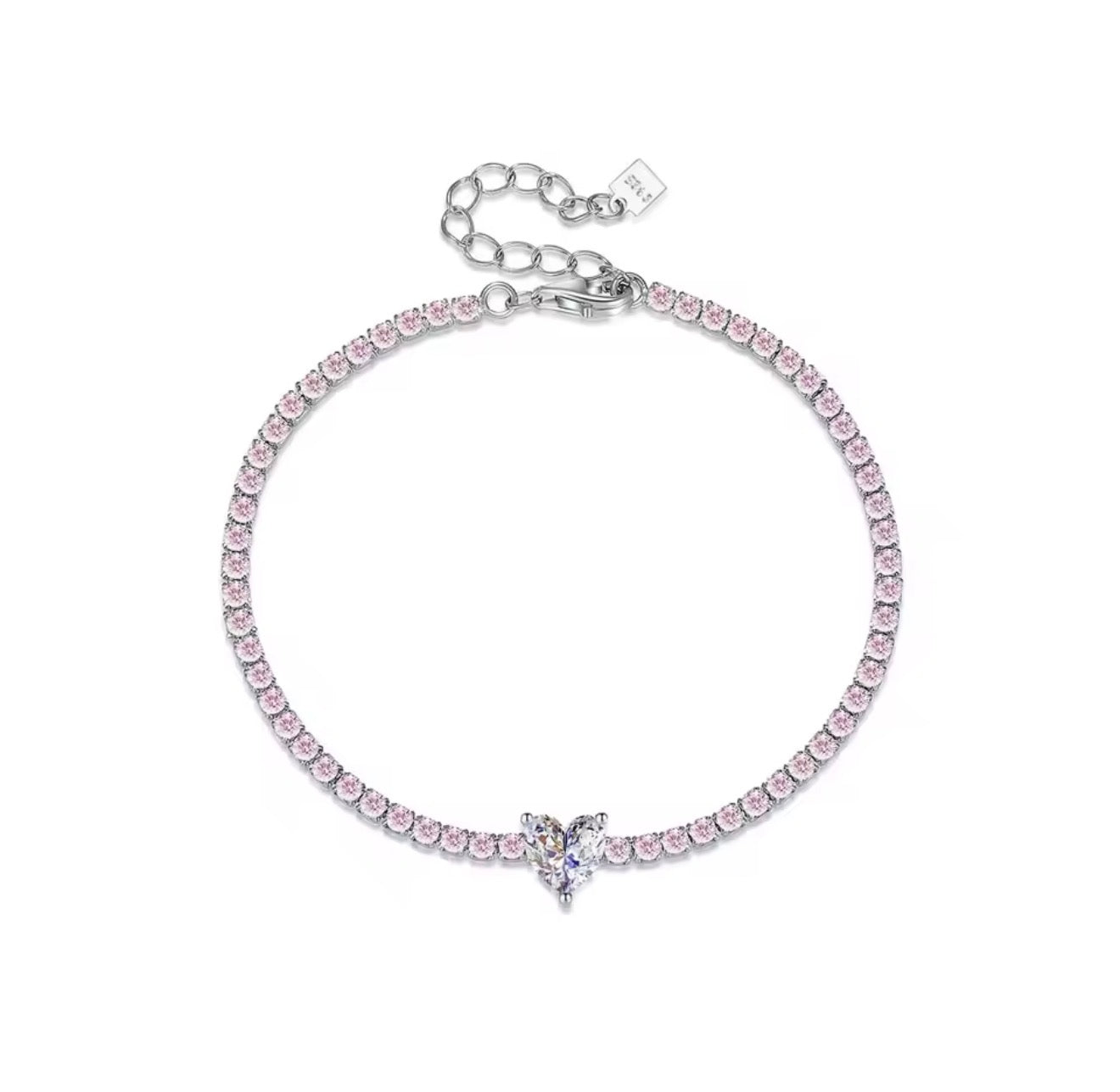 A 925 sterling silver tennis bracelet featuring a continuous row of small pastel pink round crystals anchored by a clear white heart-cut crystal centerpiece.