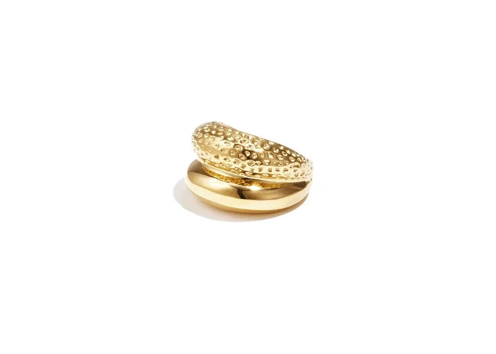 A gold-plated statement double-row ring featuring one smooth, high-polish dome band overlapping with a textured, hammered gold band. lira-textured-double-row-ring.webp