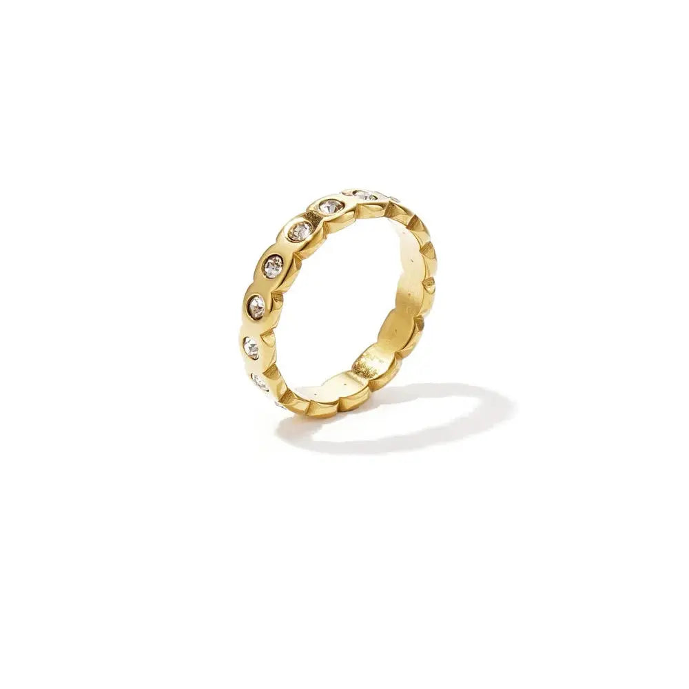 A tarnish-free gold-plated stainless steel eternity band ring featuring a continuous scalloped wave silhouette set with small circular clear bezel cubic zirconia crystals. lumi-waterproof-cz-eternity-band.webp