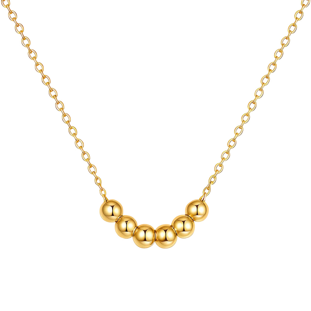 A gold necklace featuring seven polished gold beads arranged in a curve on a dainty cable chain, shown on a white background.