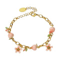 A gold link chain charm bracelet decorated with hand-painted pink enamel peaches, pink flower charms with green crystals, and tiny pink and green beads on a white background.