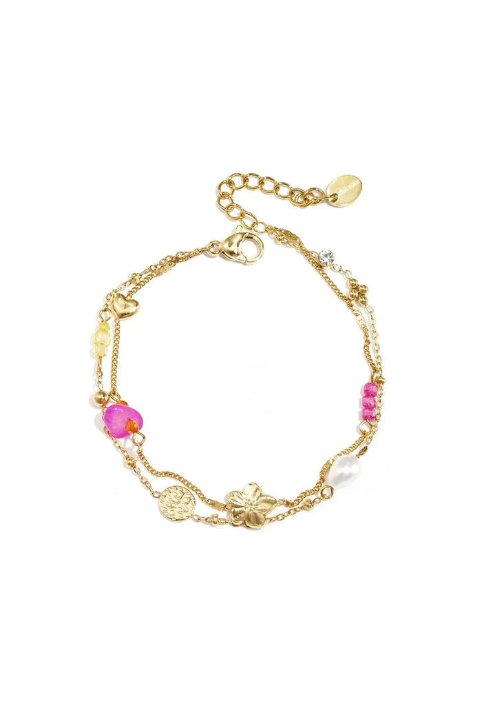 A gold-plated stainless steel double-layer charm bracelet featuring a central brushed gold flower, a hammered coin, a heart station, a white pearl, and a mix of magenta and yellow glass beads against a white background. posie-layered-eclectic-charm-bracelet.webp