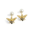 A pair of 14ct gold-plated Bill Skinner front-back earrings featuring a large white pearl stud and a detailed honeybee drop jacket lined with seed pearls and black enamel.