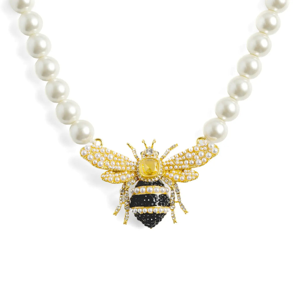 A royal pearl strand necklace by Bill Skinner featuring an oversized central 3D queen bee centerpiece detailed with a yellow crystal, black and clear rhinestones, and seed pearl wings. bill-skinner-queen-bee-pearl-necklace.webp
