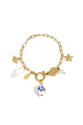 A gold-plated stainless steel charm bracelet featuring a central blue and white hand-painted porcelain floral heart, a white spiral seashell, a golden starfish, a golden ammonite shell, a bee, and a pearl drop. riviera-marine-porcelain-charm-bracelet.webp