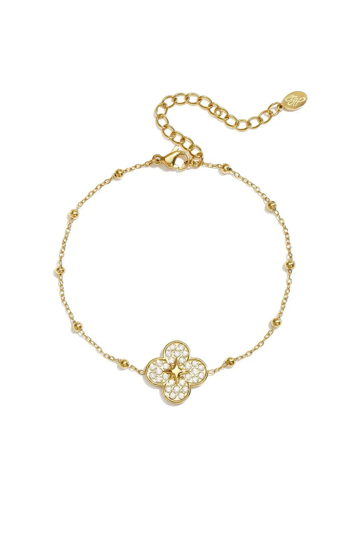 A gold-plated stainless steel satellite chain bracelet featuring a four-leaf clover charm encrusted with pave cubic zirconia and a central golden starburst motif against a white background. seraphina-pave-clover-starburst-satellite-bracelet.webp