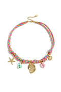 Multi-strand woven beach charm necklace in pink, green, and orange with gold sea shell charms, a ceramic heart, and a pink glass flower on a white background.
