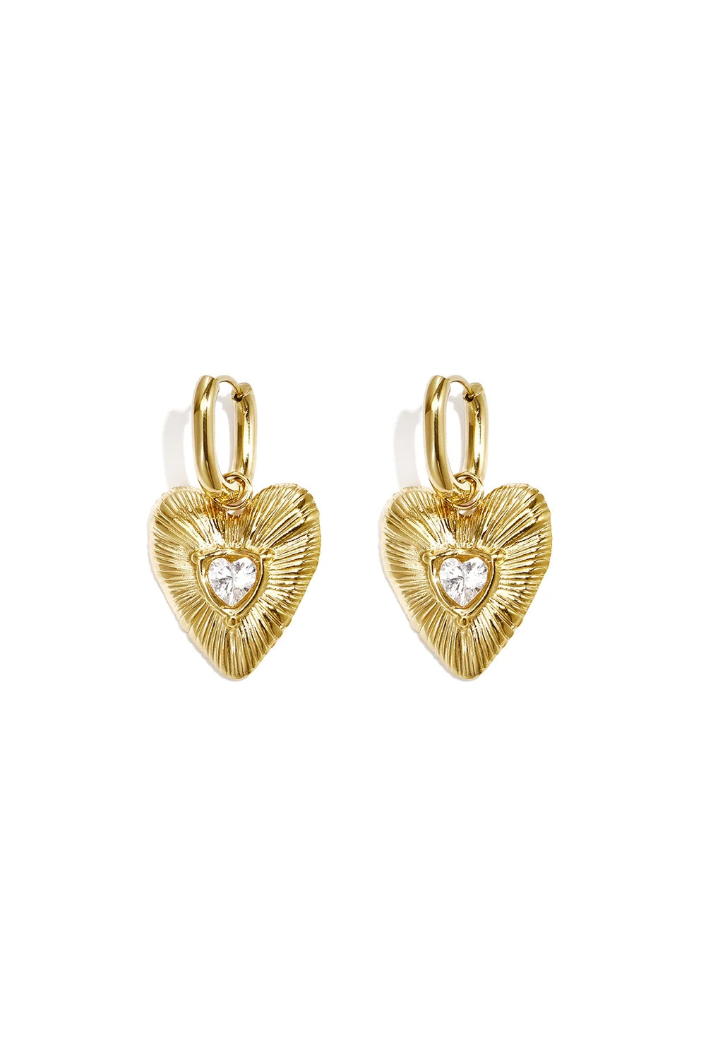 A pair of gold-plated stainless steel huggie hoop earrings featuring fluted heart charm drops with a heart-cut cubic zirconia crystal at the center against a white background. valentina-fluted-heart-crystal-huggie-earrings.webp