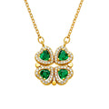 A gold transformable necklace with four emerald green heart crystals and white stone borders, shown in a closed bloom shape on a white background.