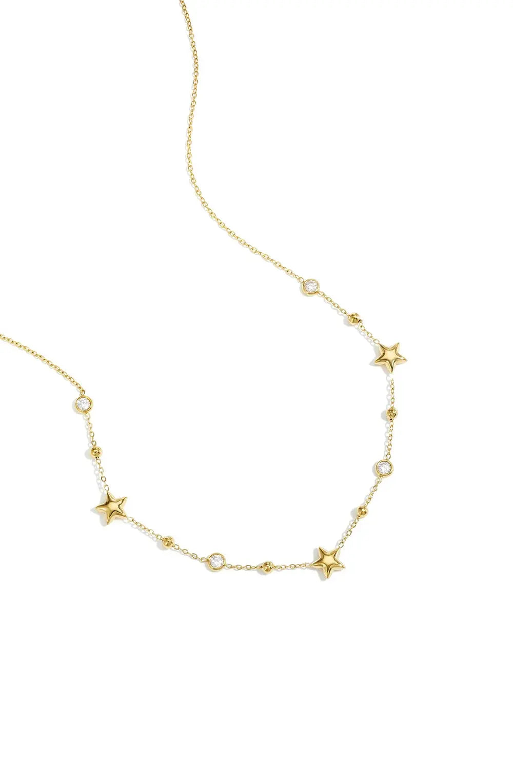 A delicate gold-plated chain necklace featuring alternating stations of small high-polish puffed stars, bezel-set clear crystals, and tiny gold satellite beads. etoile-star-crystal-station-necklace.webp